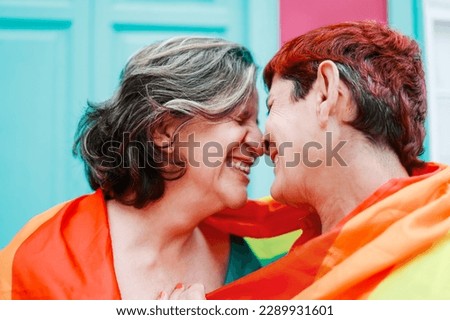 Happy gay senior lesbian couple wearing lgbt rainbow flag outdoors - Diversity family love - Main focus on right woman head Royalty-Free Stock Photo #2289931601