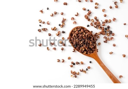 Sichuan pepper and wooden spoon set against a white background. Sichuan pepper is a member of the sansho family used in Chinese cuisine. View from above. Royalty-Free Stock Photo #2289949455