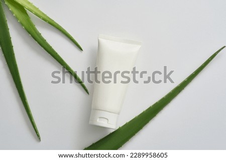 Mockup scene for cosmetic, cleanser or moisturizer product from aloe vera ingredient with white plastic tube unlabeled and fresh aloe vera leaves decorated on white background. Space for design. Royalty-Free Stock Photo #2289958605