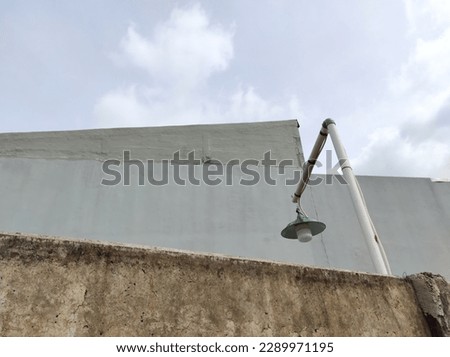 Custom-made street lamps or street light using pipes. Grey wall and cloudy sky background. Landscape.