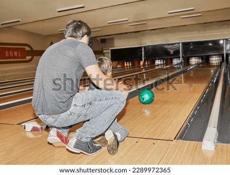 A Father helping his Young Son Bowl