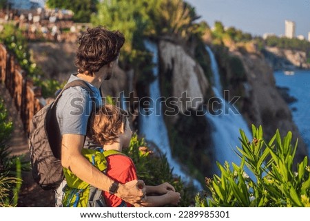 Father and son tourists on the background of Duden waterfall in Antalya. Famous places of Turkey. Lower Duden Falls drop off a rocky cliff falling from about 40 m into the Mediterranean Sea in amazing
