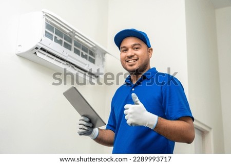 Technician in uniform using tablet to check list of maintenance and cleaning filters of air conditioner. Air condition maintenance service. Home services concept. Royalty-Free Stock Photo #2289993717