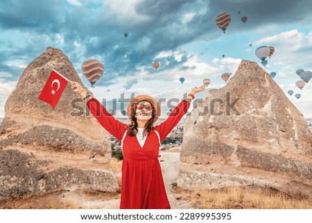 Discover the magic of Cappadocia, Turkey as a young woman proudly displays the Turkish flag and watches the iconic hot air balloons float across the sky.