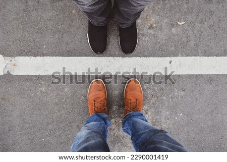 Man and woman standing close on either side of white line. Couple relationship concept. Royalty-Free Stock Photo #2290001419