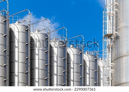Stainless steel silos against the blue sky. Warehouses for storage of plastics and bulk grains. Royalty-Free Stock Photo #2290007361