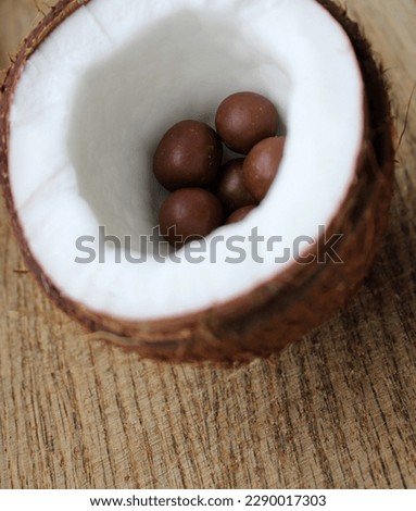 Half Of Coconut With Smooth Chocolate Candies With Nuts Inside Closeup Stock Photo
