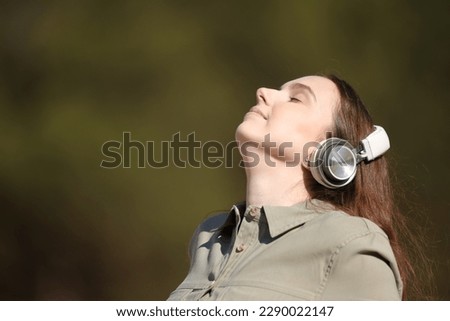 Woman meditating outside listening audio guide with headphone