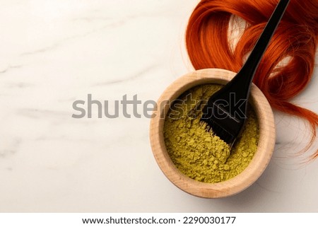 Henna powder, brush and red strand on white marble table, flat lay with space for text. Natural hair coloring