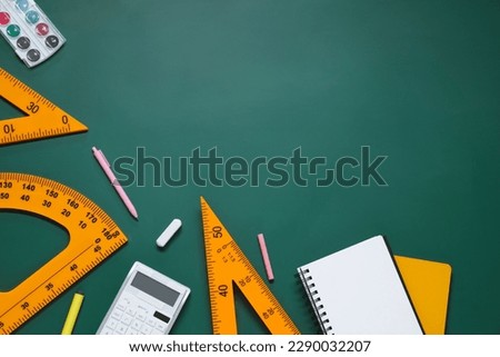 Flat lay composition with protractor, triangle and stationery on green chalkboard. Space for text
