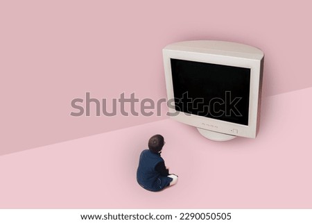 A little boy sits next to a big old crt monitor and looks at it. Pink background.