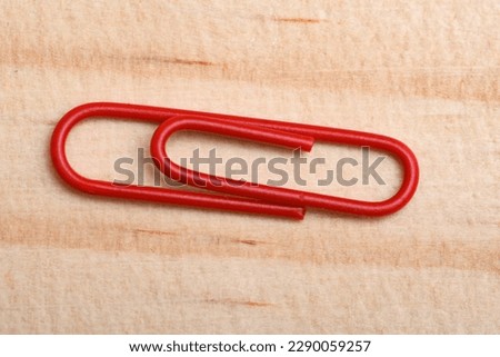 Red paper clip on a wooden board