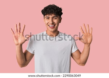 Young latin man receiving a pleasant surprise, excited and raising hands.