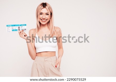 Young beautiful smiling blond female. Carefree woman isolated on white background. Positive model hold boarding pass ticket. Excited tourist. Passenger travel abroad weekend getaway air flight journey