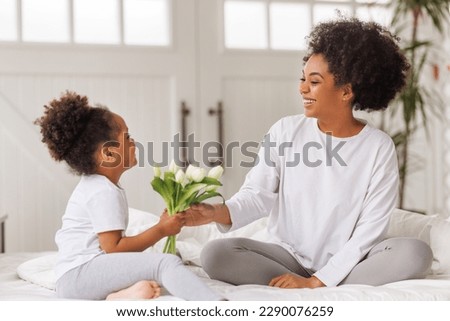 Happy mother's day! Afro american family happy baby daughter congratulates mom on the holiday gives bouquet of flowers at home