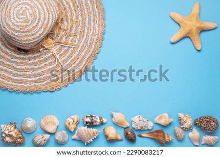 Summer and vacation flat lay with woman straw hat, a star fish and various seashells at the lower edge of the picture on blue background.