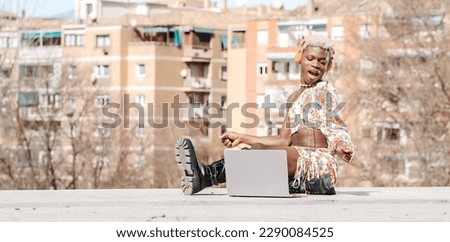 Positive black transgender person typing on laptop on stairs