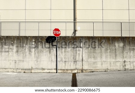 Stop road sign at the roadside with grunge concrete wall and railing on behind and asphalt road in front. Background for copy space.
