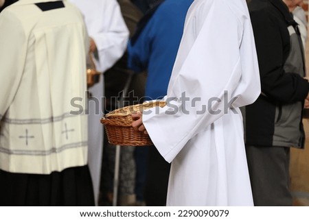 The altar boy collects donations to the basket from the faithful in the Catholic Church. Victim. Royalty-Free Stock Photo #2290090079