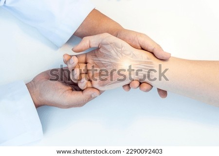The orthopedic doctor or surgeon in uniform examined the patient with numbness of hand.Wrist pain in carpal tunnel syndrome with transparent anatomy of median nerve.Light effect on white background. Royalty-Free Stock Photo #2290092403