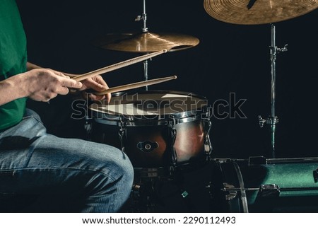 A man plays the snare drum against a dark background.