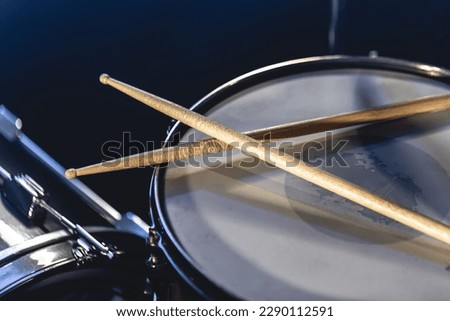 Close-up, snare drum and drumsticks on a dark background.