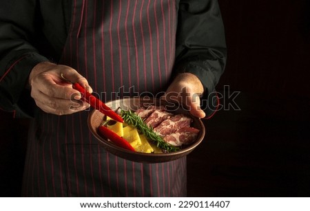 Chef puts red peppers on a plate with sliced ham and cheese. Black space for recipe or menu