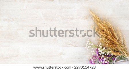 Ripe yellow wheat bouquet with purple and white flowers, on a white wooden surface. Intended for a greeting card for the holiday of Shavuot Royalty-Free Stock Photo #2290114723