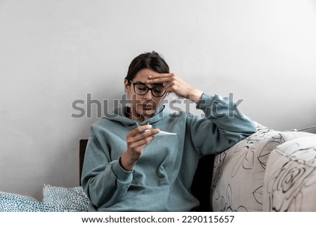Ill upset young woman sitting on sofa covered with blanket freezing blowing running nose got fever caught cold sneezing in tissue, sick girl having influenza symptoms coughing at home, flu concept Royalty-Free Stock Photo #2290115657