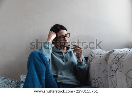 Ill upset young woman sitting on sofa covered with blanket freezing blowing running nose got fever caught cold sneezing in tissue, sick girl having influenza symptoms coughing at home, flu concept Royalty-Free Stock Photo #2290115751