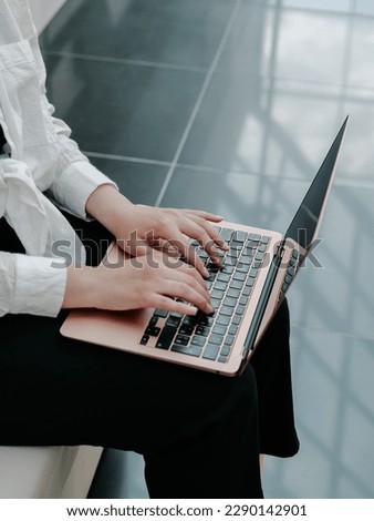 Woman holding a laptop in her hands and typing on the keyboard, close-up