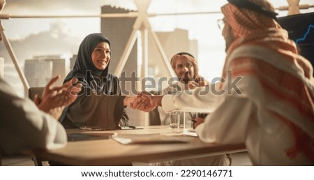 Muslim Businesspeople Closing a Business Deal at a Corporate Modern Office. Female and Male Representatives Shake Hands and Celebrate Successful Partnership. Saudi, Emirati, Arab Office Concept Royalty-Free Stock Photo #2290146771