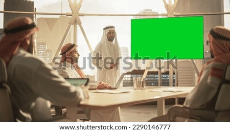 Arab Businessman Shows Data to a Group of Saudi Investors. TV Screen with Green Screen Mock Up Display. Business Meeting Presentation in Conference Room in Modern Office Royalty-Free Stock Photo #2290146777