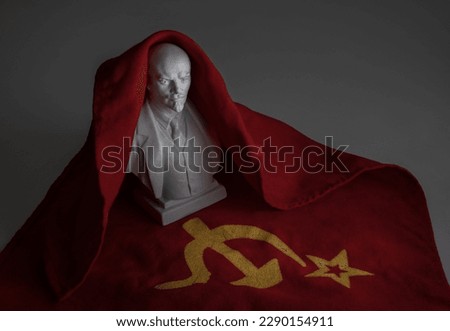 Ceramic bust of Lenin against the background of the red flag of the Soviet Union with a hammer and sickle. Royalty-Free Stock Photo #2290154911