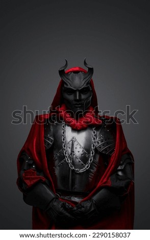 Portrait of dark member of mysterious cult dressed in red robe and black mask. Royalty-Free Stock Photo #2290158037