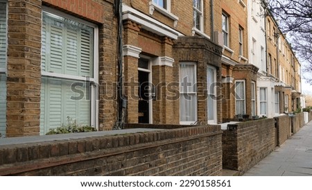 Typical Victorian terraced houses in England. Exterior view of cozy residential buildings in London with brick fence, several floors, windows and front door with molding. Real estate, Living apartment Royalty-Free Stock Photo #2290158561