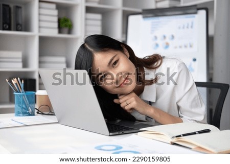 Portrait of young pretty businesswoman smiling to the camera while sitting at her office desk.