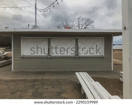 Wooden benches outside sealed up snack shop along beach in the winter with overcast sky