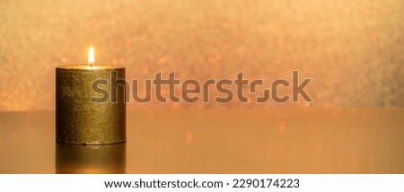 a golden candle in front of a golden glittering background  for banner, panorama or border with copy space