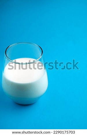 picture of a glass of milk half full on a blue background