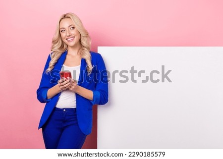 Photo of dreamy sweet woman dressed blue blazer texting device looking placard empty space isolated pink color background