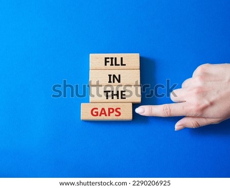 Fill in the gaps symbol. Concept words fill in the gaps on wooden blocks. Beautiful blue background. Business and fill in the gaps concept. Copy space.