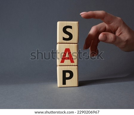 SAP - Systems Applications Products. Wooden cubes with word SAP . Businessman hand. Beautiful grey background. Business and System Application Product concept. Copy space.