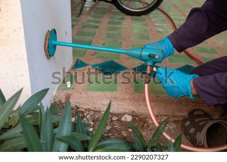 exterminate termite control company employee is using a termite sprayer at customer's house and searching for termite nests to eliminate. exterminate control worker spraying chemical insect repellant Royalty-Free Stock Photo #2290207327
