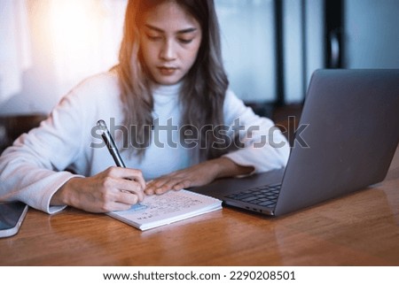 A female college student with a laptop doing research and self-study in the study room. Education stock photo