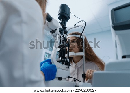 A young woman at a doctor's appointment. An optometrist examines the patient's vision using a slit lamp. Royalty-Free Stock Photo #2290209027