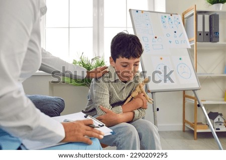 Sad child at session in psychologist's office. Specialist trying to understand depressed, upset little school student boy, support him and help cope with problems and troubles. Mental health concept Royalty-Free Stock Photo #2290209295
