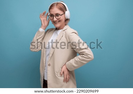 mature woman in a jacket listening to music in wireless headphones