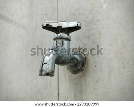 photo of a water faucet with a dirty wall