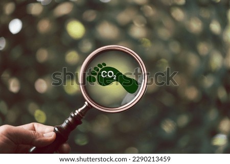 Carbon footprint with magnifying glass on green background. Carbon Footprint is total amount of carbon dioxide and greenhouse gases such as methane, Nitrous Oxide gas, emitted from services. Royalty-Free Stock Photo #2290213459
